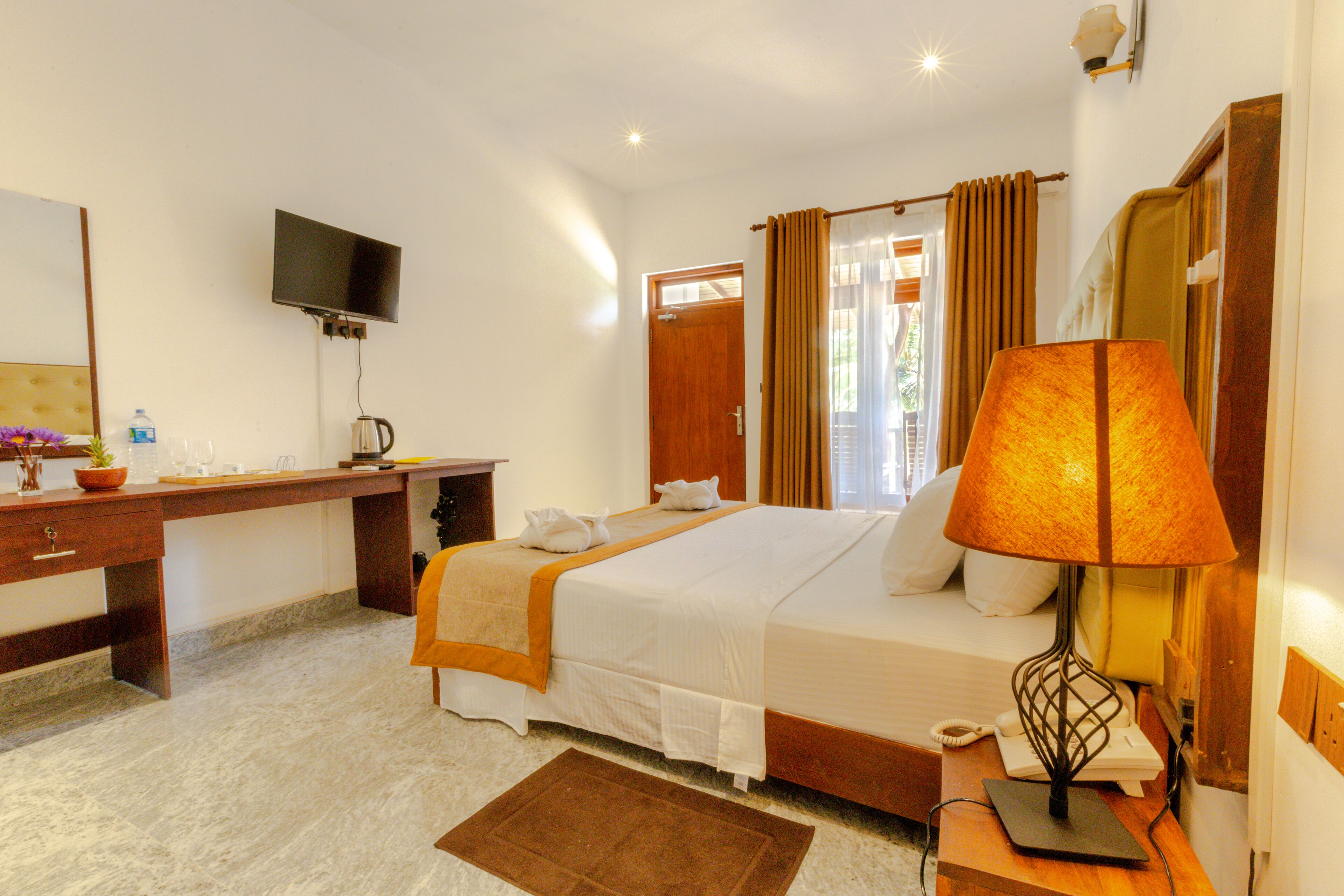 A hotel room with a bed, desk, and a TV mounted on the wall.