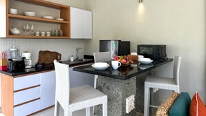A compact kitchen with a dining area, equipped with a refrigerator, microwave, and a coffee maker. - MaySa Villa Uluwatu (Pecatu)