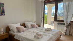 Un dormitorio con una cama grande, dos mesitas de noche, una ventana con cortinas y vistas al exterior.
