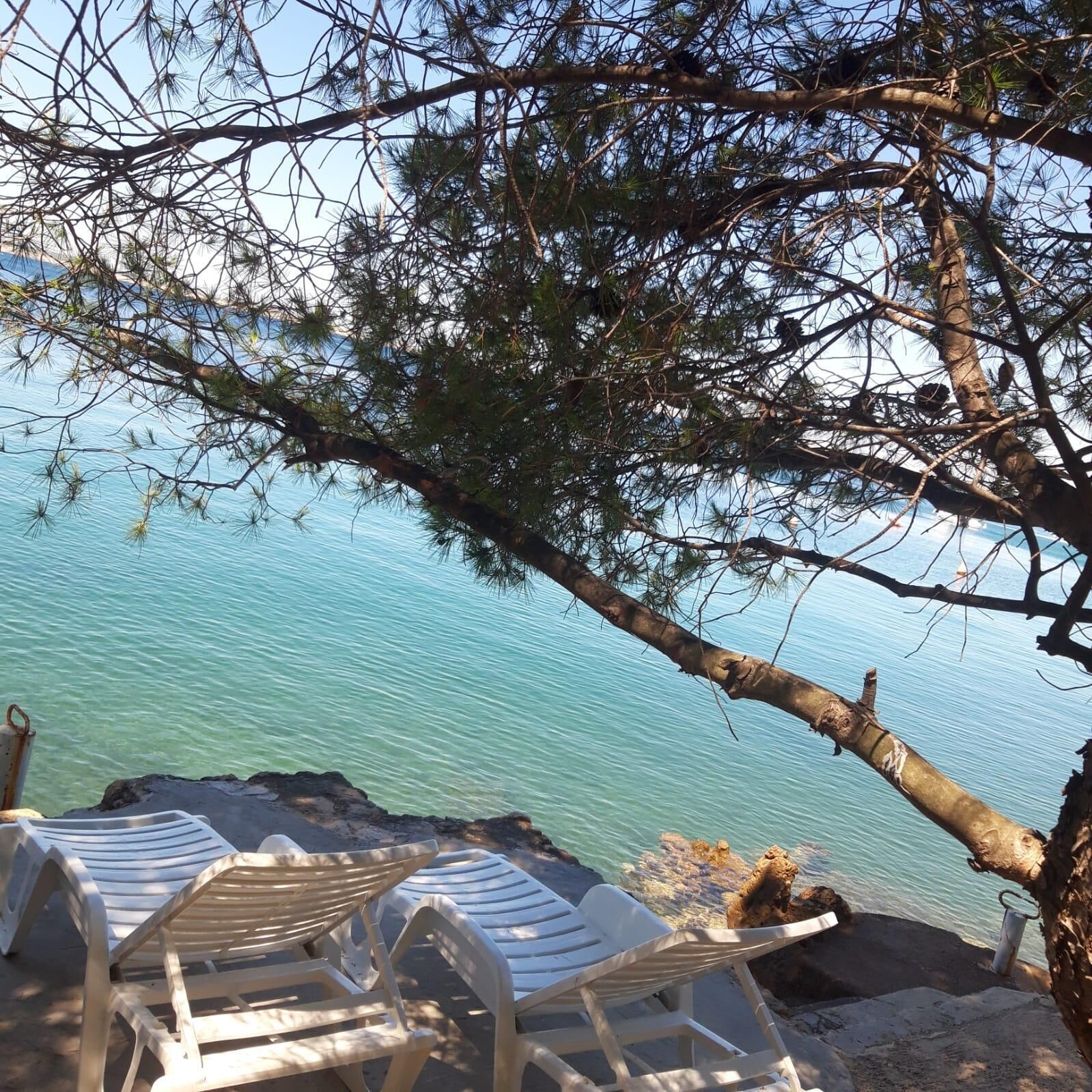 A beach with lounge chairs and a rocky shoreline.