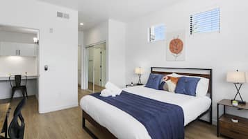Un dormitorio moderno con una cama grande, mesitas de noche, un escritorio y una silla.