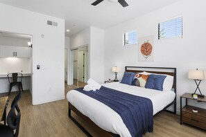 A modern bedroom with a large bed, bedside tables, a desk, and a chair. - CozySuites Glendale with pool  04 and 18 (Glendale)
