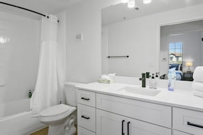 A modern bathroom with a white sink, toilet, and bathtub. - CozySuites Glendale with pool  04 and 18 (Glendale)