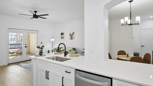 A modern kitchen with white cabinetry, a built-in dishwasher, and a large island with a sink. - CozySuites Glendale with pool  04 and 18 (Glendale)