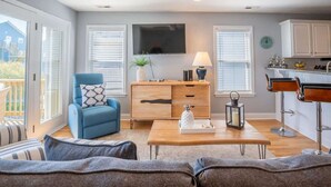 A modern living room with a blue armchair, a wooden coffee table, and a TV mounted on the wall.