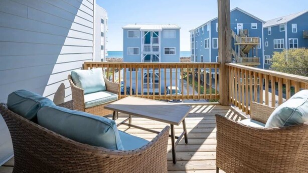 A wooden deck with wicker furniture and a view of buildings in the background.