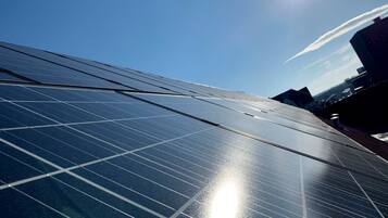 A close-up of solar panels with a clear sky and a building in the background.
