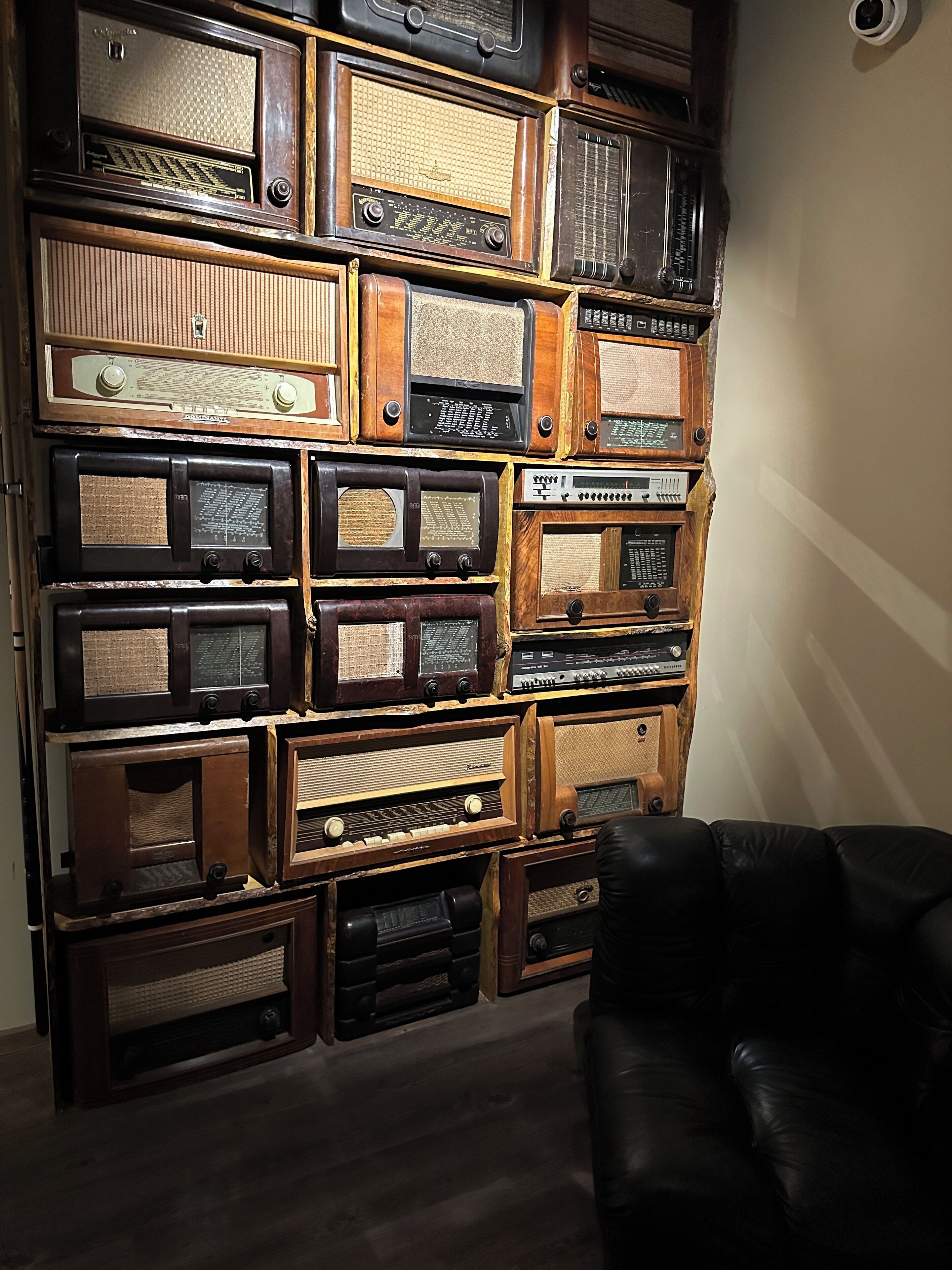 A wall of vintage radios in various sizes and designs, arranged in a grid pattern.