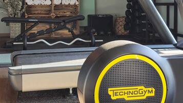 Un gimnasio en casa con una bicicleta estática Technogym, estantes para pesas y una pesa rusa.