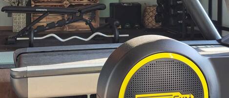 Une salle de sport à domicile équipée d’un vélo d’appartement Technogym, de supports pour haltères et d’un kettlebell.