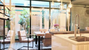 A modern kitchen with a central island, stainless steel appliances, and a large window overlooking a garden. - PHIL & MAX Hotel & Apartments Messe (Laatzen)