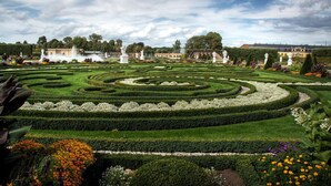 A formal garden with geometric hedges and statues, surrounded by buildings. - PHIL & MAX Hotel & Apartments Messe (Laatzen)