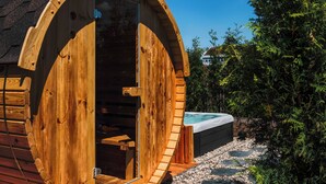 A wooden cabin with a circular door, a small outdoor seating area, and a hot tub. - PHIL & MAX Hotel & Apartments Messe (Laatzen)