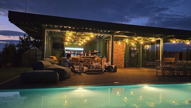 An outdoor pool area with a covered seating area, a bar, and a stone wall. - PHIL & MAX Hotel & Apartments Messe (Laatzen)