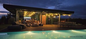 Un área de piscina al aire libre con una zona de estar cubierta, un bar y una pared de piedra.