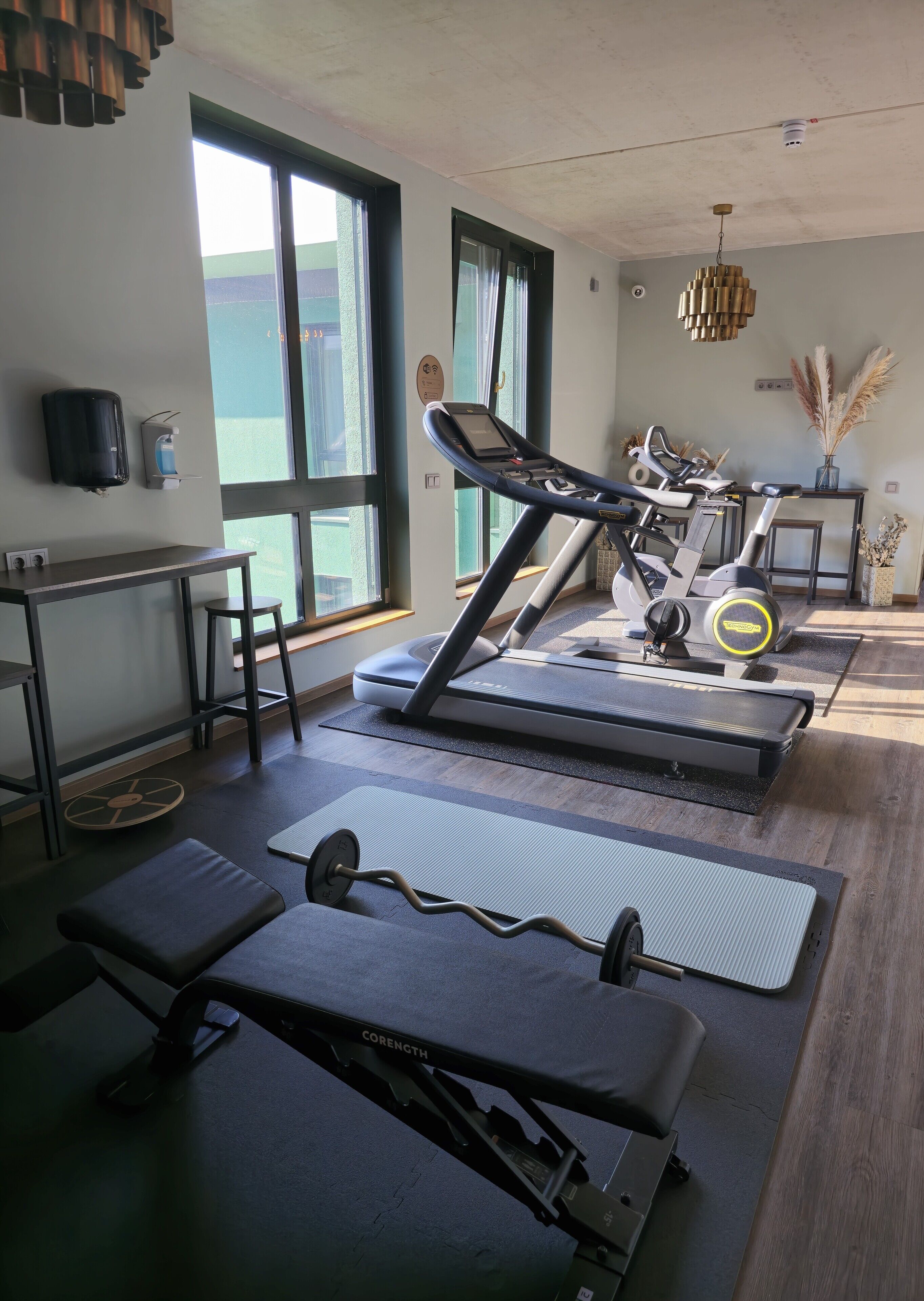 A gym with exercise equipment, a water dispenser, and large windows.