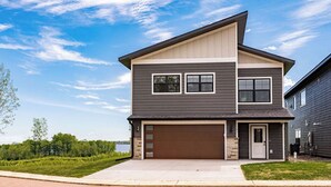 A two-story house with a garage, a front door, and a driveway. - RiverWest Hunters Landing - Hot Tub - Riverfront - Dogs (Duluth)