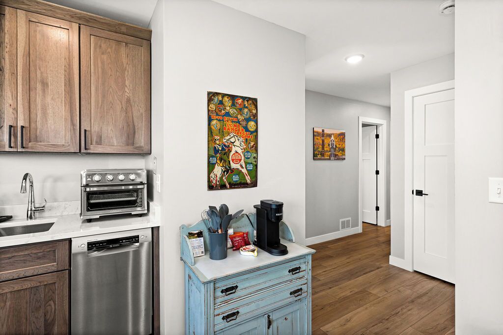 A kitchen with wooden cabinets, a stainless steel dishwasher, and a coffee maker on a blue cabinet.