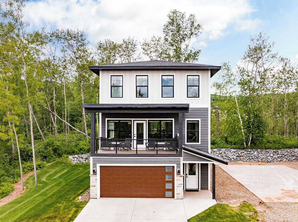Une maison moderne à deux étages, dotée d’un grand garage, d’un balcon et d’une pelouse bien entretenue.
