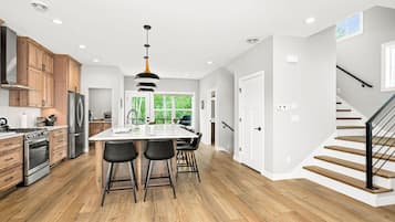 Une cuisine moderne avec des meubles en bois, des appareils électroménagers en acier inoxydable et un îlot central doté de tabourets de bar.