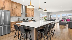 Una cocina moderna con armarios de madera, electrodomésticos de acero inoxidable y una isla central con taburetes de bar.