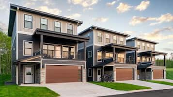 A modern two-story residential building with a garage, a covered outdoor seating area, and a bicycle parked outside.