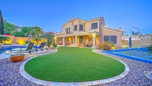 A two-story house with a swimming pool, a patio with outdoor furniture, and a well-maintained lawn. - Desert Paradise, Pool, Spa, Pickleball, Putt Green (Phoenix)