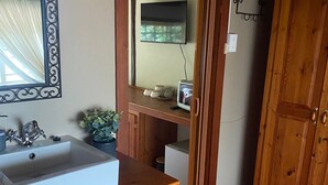 Une cuisine équipée d’un évier, de meubles de rangement en bois, d’un miroir et d’un téléviseur.