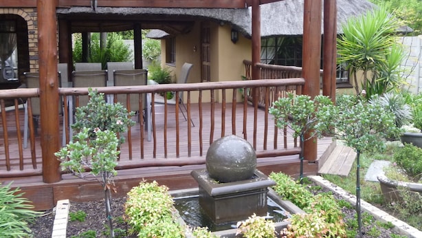 Un espace extérieur abrité, doté d’une pergola en bois, de sièges et d’un élément décoratif aquatique.