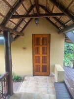 Una puerta de madera con un ventanal, un acceso con azulejos y una estructura de techo de paja.