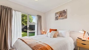 Une chambre à coucher avec un grand lit, une table de chevet, une lampe et un tableau au mur.