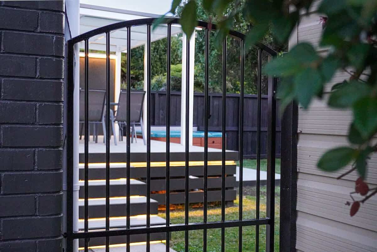 Une cour arrière clôturée, avec des marches menant à une terrasse, le tout entouré d’une clôture et d’une maison.