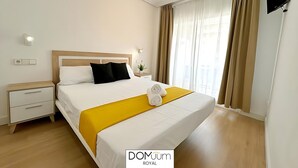 A hotel room with a bed, a nightstand, a TV, and a window with curtains.