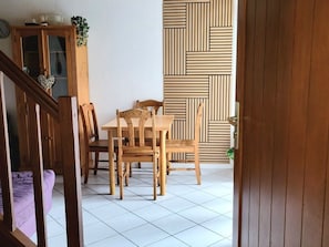 Uma sala de jantar com mesa e cadeiras de madeira, um armário com portas de vidro e parede com padrão.