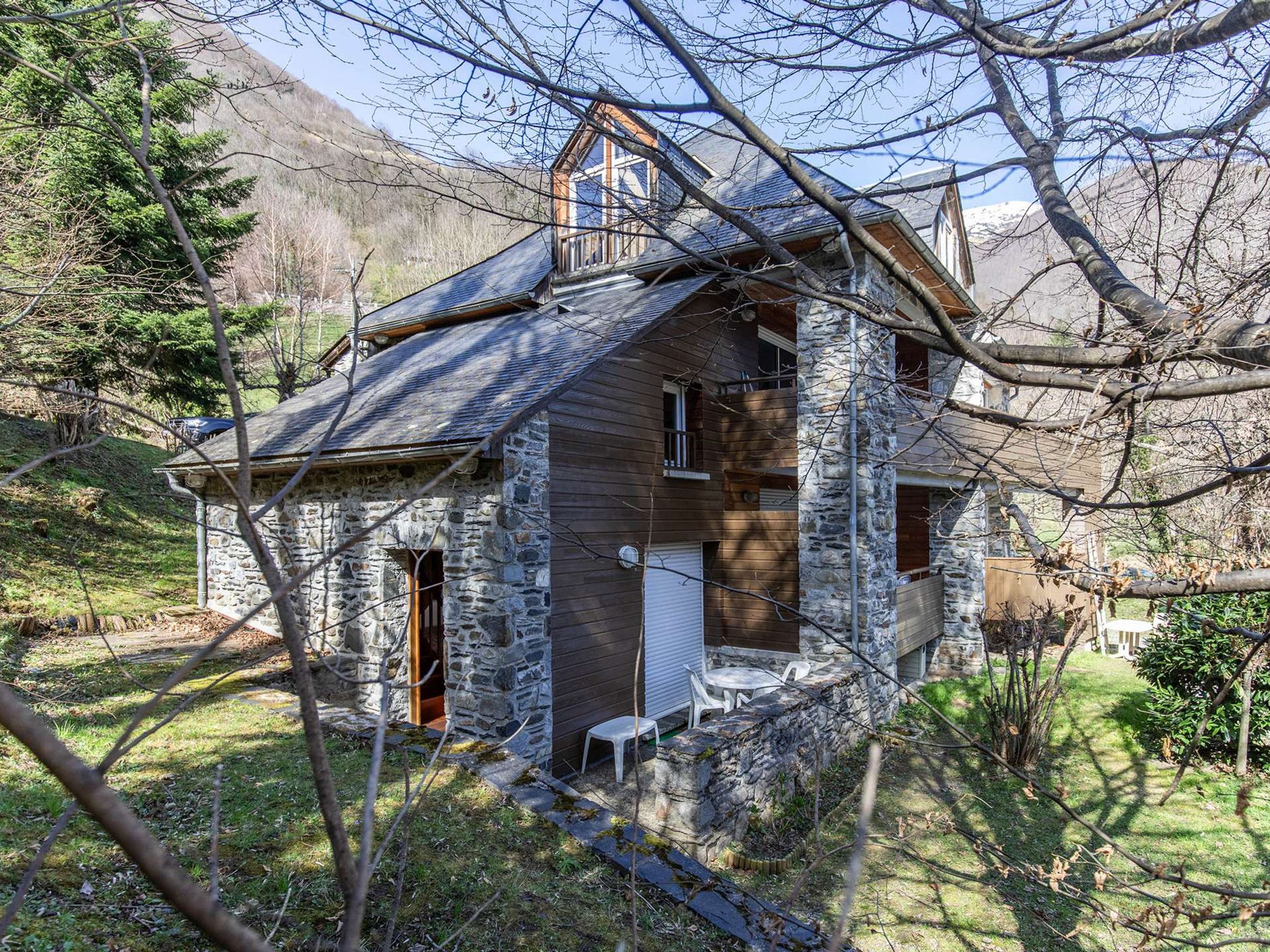 A rustic stone house with a sloped roof, a small porch, and a single visible window.
