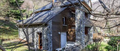 A rustic stone house with a sloped roof, a small porch, and a single visible window.