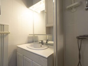 A bathroom with a white sink, mirror, and shower.