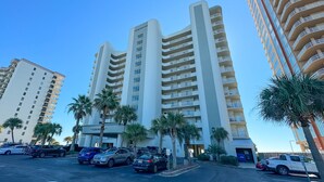 A multi-story hotel with a modern design, featuring balconies on each floor and a parking area with several cars. - Tidewater 907-Family friendly complex to enjoy the Beach! (Orange Beach)