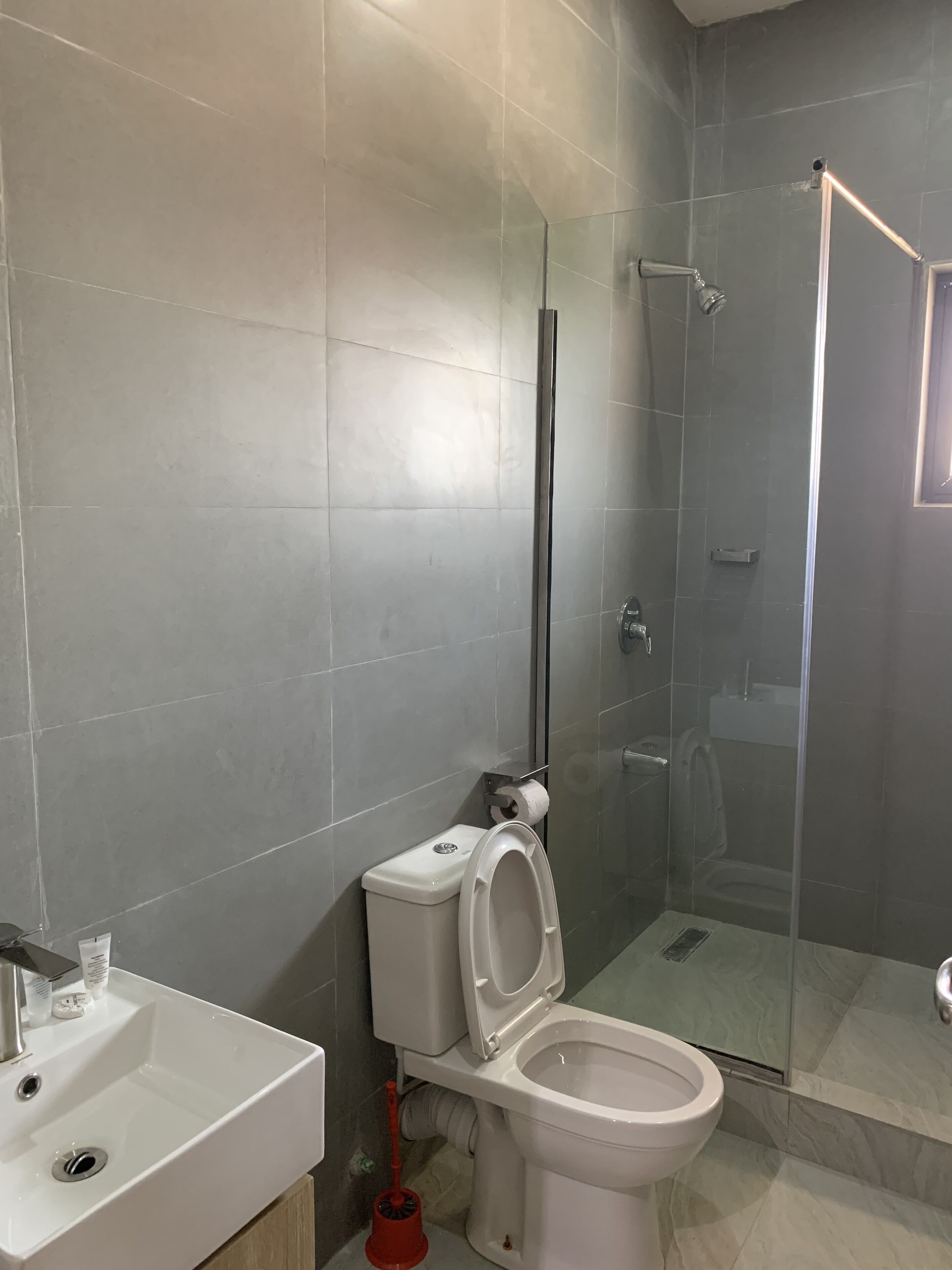 Un baño moderno con inodoro, lavamanos y ducha con mampara de vidrio.