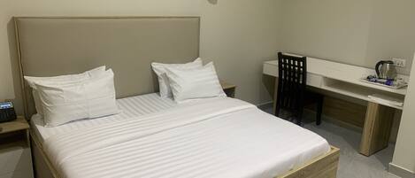 A neatly arranged hotel room with a bed, a desk, and a chair.