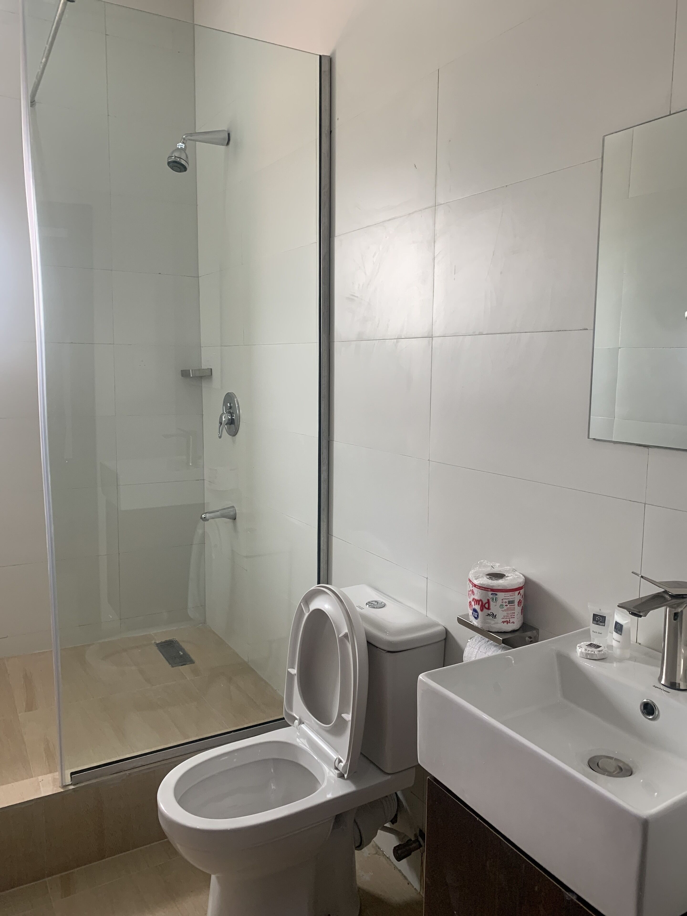 A bathroom with a glass-enclosed shower, a toilet, and a sink.