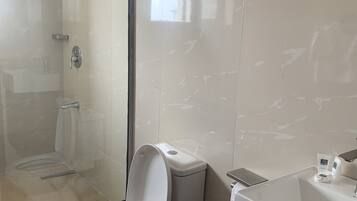 Une salle de bain moderne avec une douche à parois de verre, des toilettes et un lavabo équipé de produits de toilette.