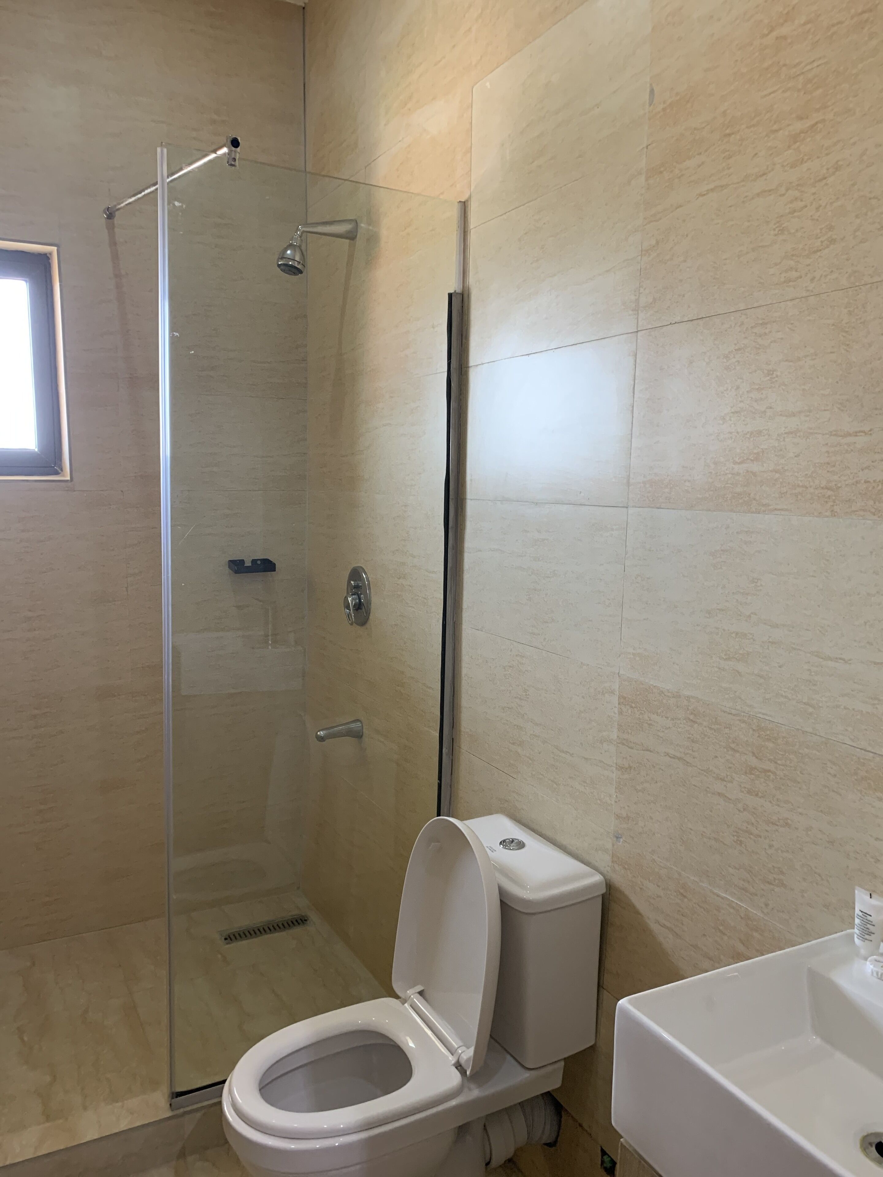 A modern bathroom with a glass-enclosed shower, a white toilet, and a sink.