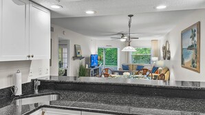 Eine moderne Küche mit schwarzer Granit Arbeitsplatte, weißen Schränken und einem Essbereich mit Tisch und Stühlen.