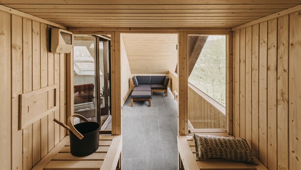 Un interior de madera con un sofá y una mesa, una ventana y piso de madera.