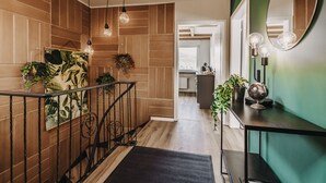 Un pasillo moderno con paneles de madera, barandilla de metal negro y lámparas colgantes.