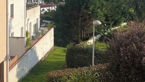 Een woonwijk met een grote boom, een gebouw met een pannendak en een heldere lucht.