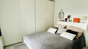 Een slaapkamer met een bed, een bankje, een kast en een nachtkastje.