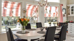 A dining area with a white table, black chairs, and a vase of orange flowers. - Lovely home in Söderköping with sauna (Söderköping)