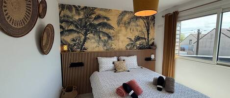 Une chambre à coucher avec un lit, une lampe suspendue, un tableau au mur et une fenêtre.